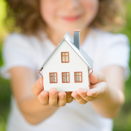 Child holding house in hands outdoors